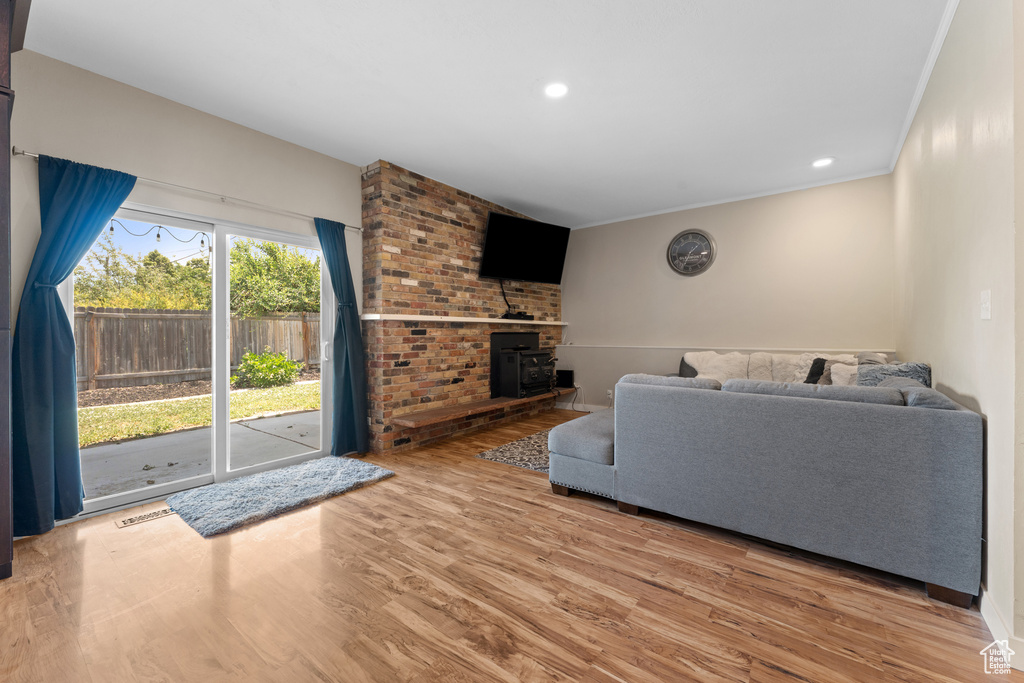 Living room with a wood stove, wood finished floors, recessed lighting, and crown molding