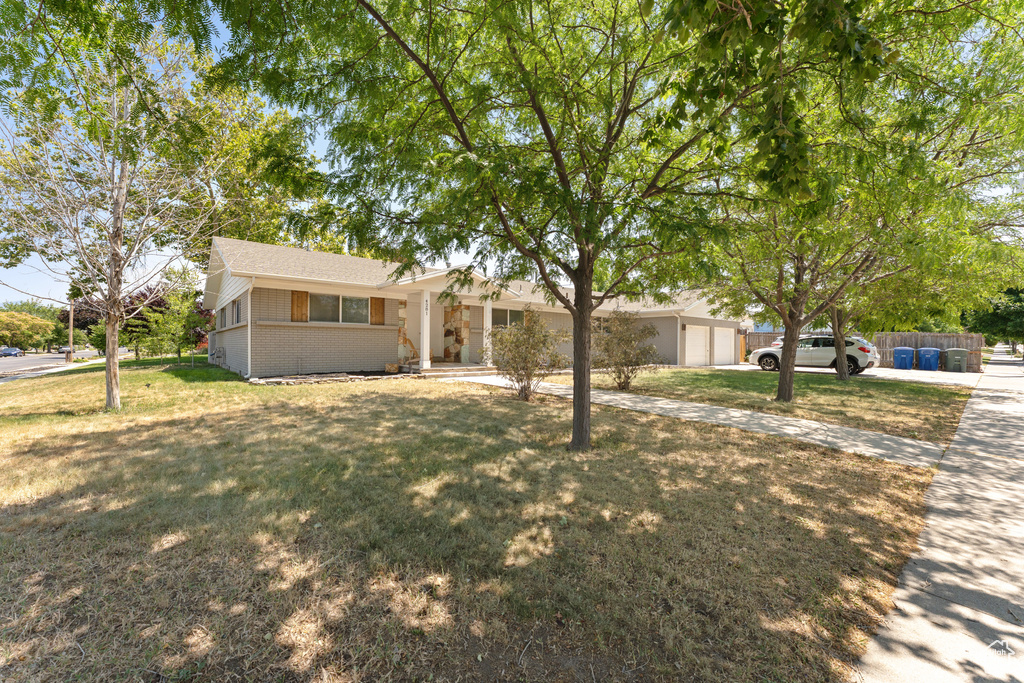 Single story home featuring brick siding, driveway, a front lawn, and a garage