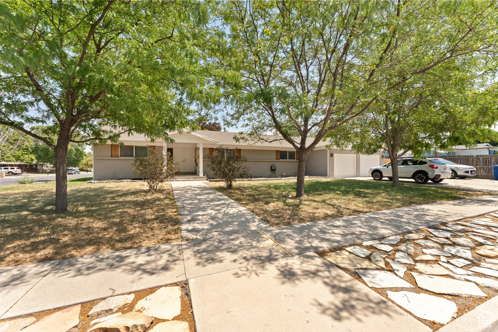 View of front of property featuring driveway, brick siding, and a front yard