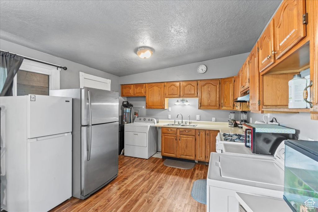 Kitchen featuring washer / dryer, freestanding refrigerator, a textured ceiling, and light wood finished floors