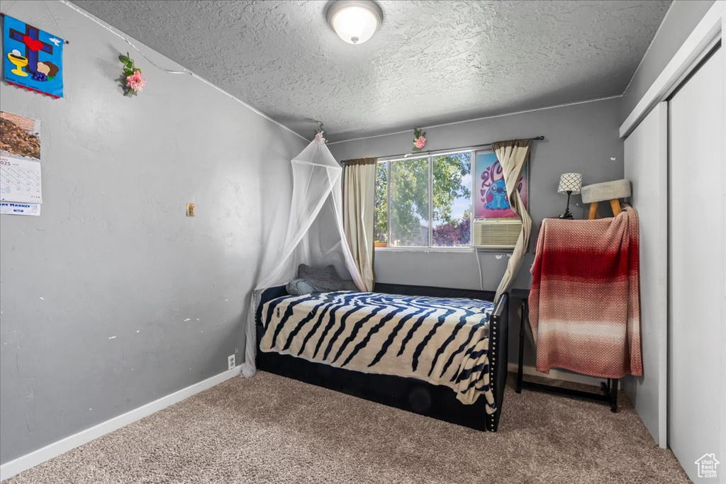 Bedroom with carpet floors, a textured ceiling, and a closet
