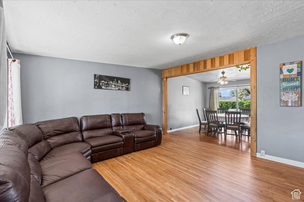 Living room with light wood-style floors, a ceiling fan, and a textured ceiling