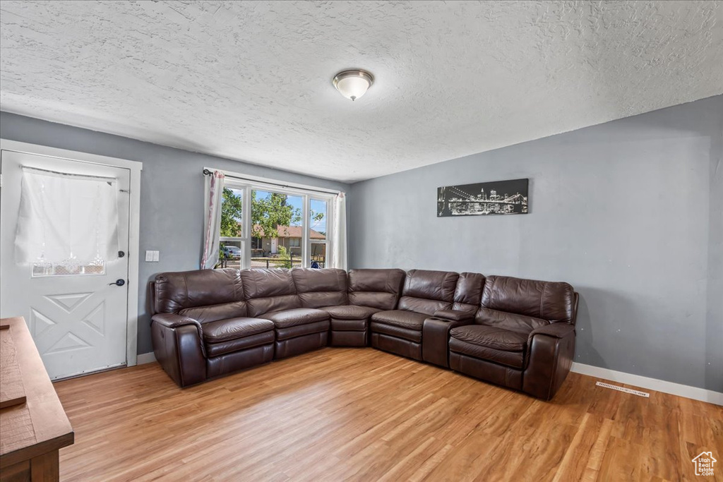 Living room with a textured ceiling and light wood finished floors