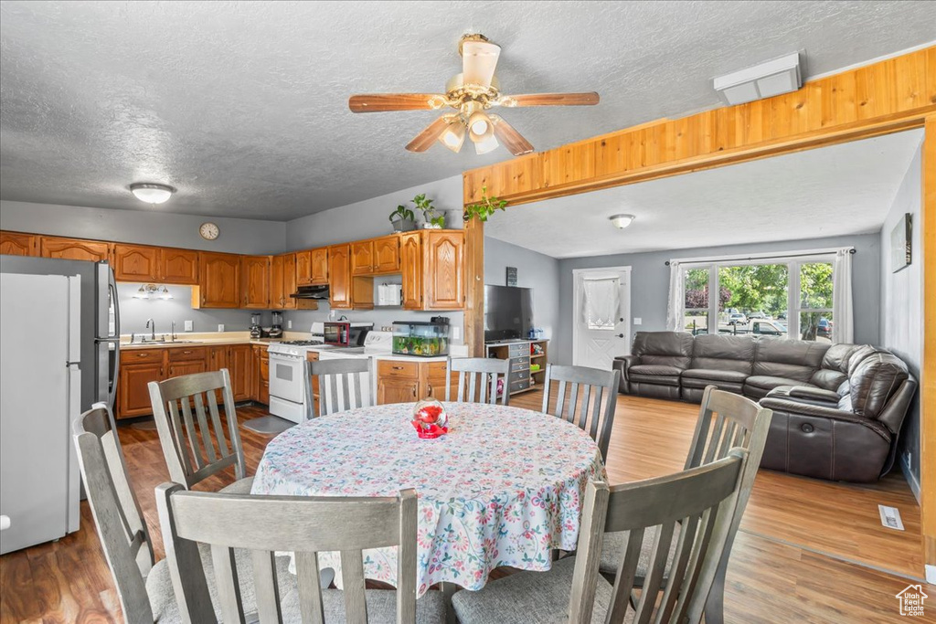 Dining space with wood finished floors, a textured ceiling, and ceiling fan