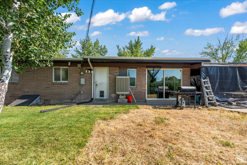 Back of property with brick siding and a yard