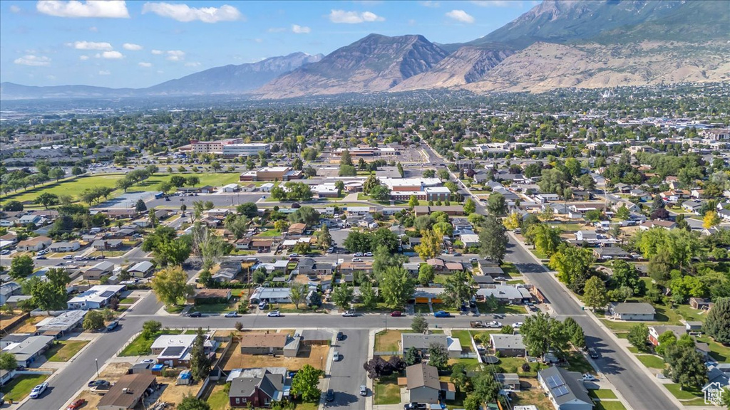 Aerial view of property and surrounding area featuring mountains and nearby suburban area