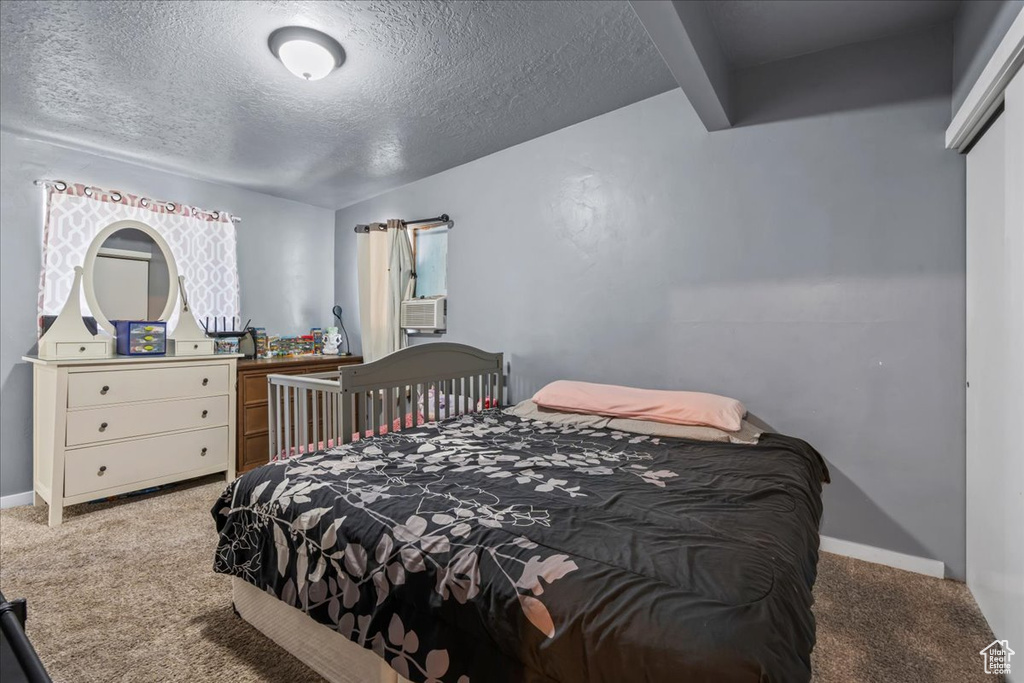 Carpeted bedroom featuring a textured ceiling and cooling unit