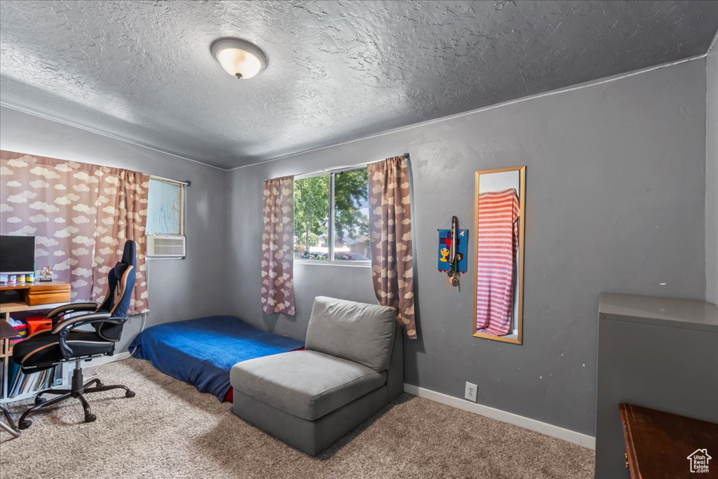 Carpeted bedroom with a textured ceiling, an office area, and cooling unit