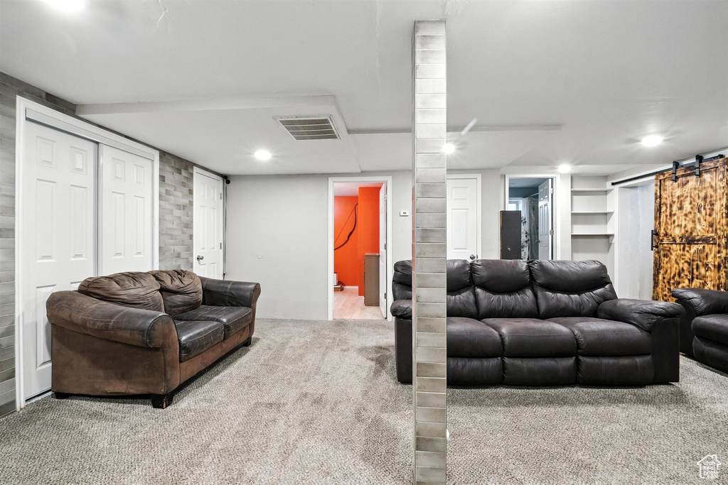 Carpeted living area with a barn door and recessed lighting