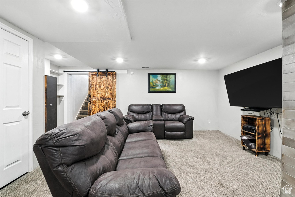 Carpeted living area featuring a barn door and recessed lighting