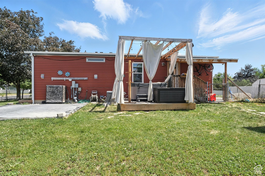Back of house with a hot tub and a patio