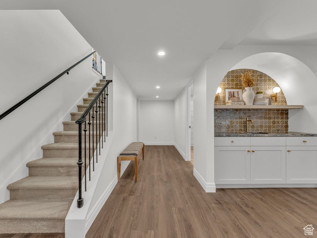 Corridor with wood finished floors, stairway, and recessed lighting