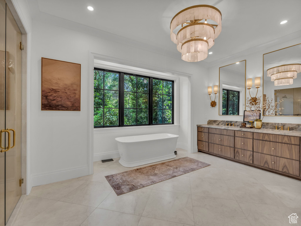 Bathroom with double vanity, a freestanding tub, a shower stall, recessed lighting, and a chandelier