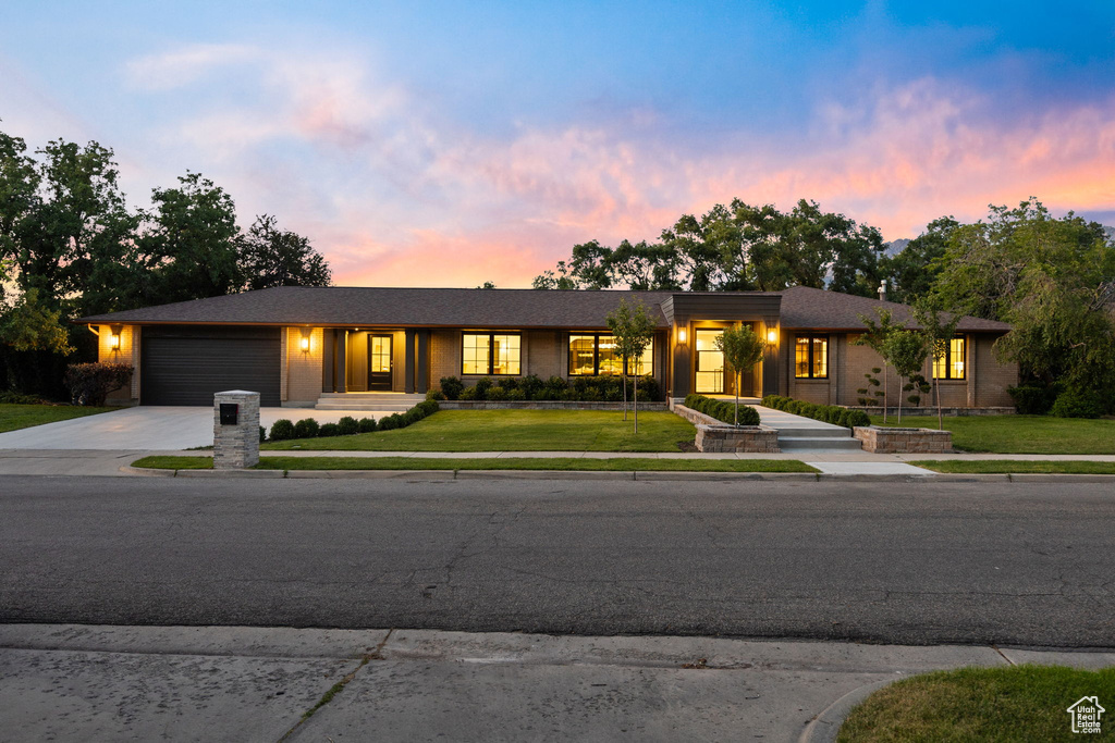 View of front facade featuring concrete driveway, a garage, and a yard