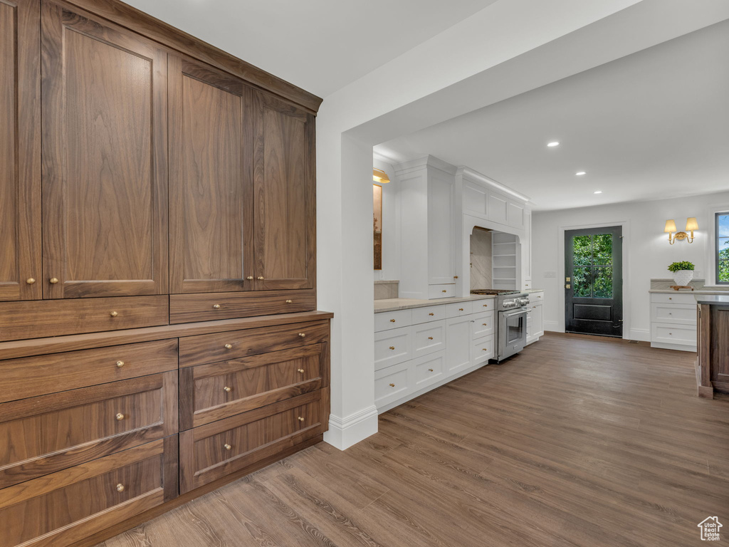 Kitchen with high end stove, wood finished floors, white cabinetry, recessed lighting, and light countertops