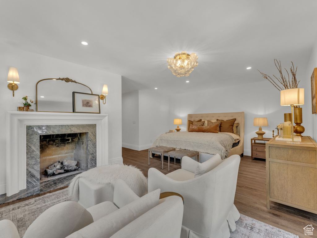 Bedroom featuring wood finished floors, recessed lighting, a chandelier, and a premium fireplace