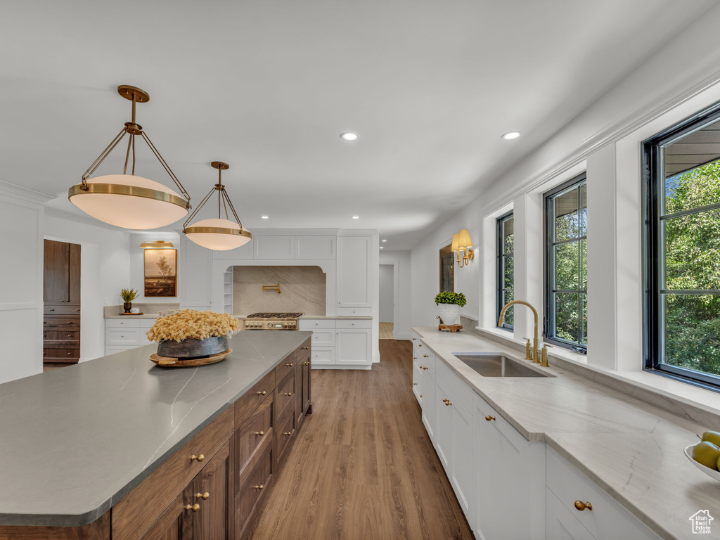 Kitchen with white cabinetry, light wood finished floors, recessed lighting, decorative light fixtures, and range