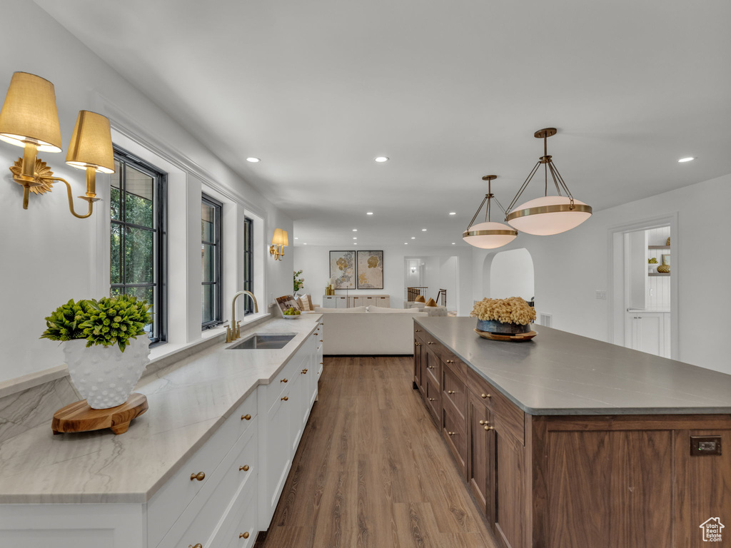 Kitchen with a large island, white cabinetry, open floor plan, wood finished floors, and recessed lighting