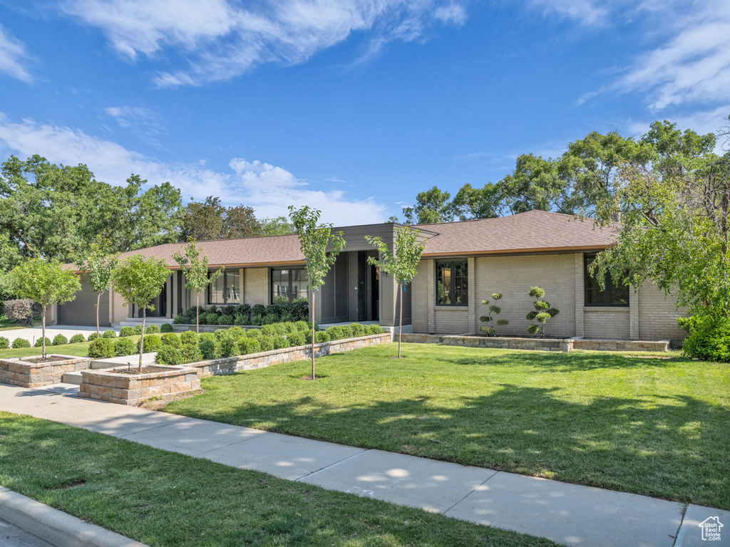 Ranch-style house featuring brick siding, a front lawn, and roof with shingles