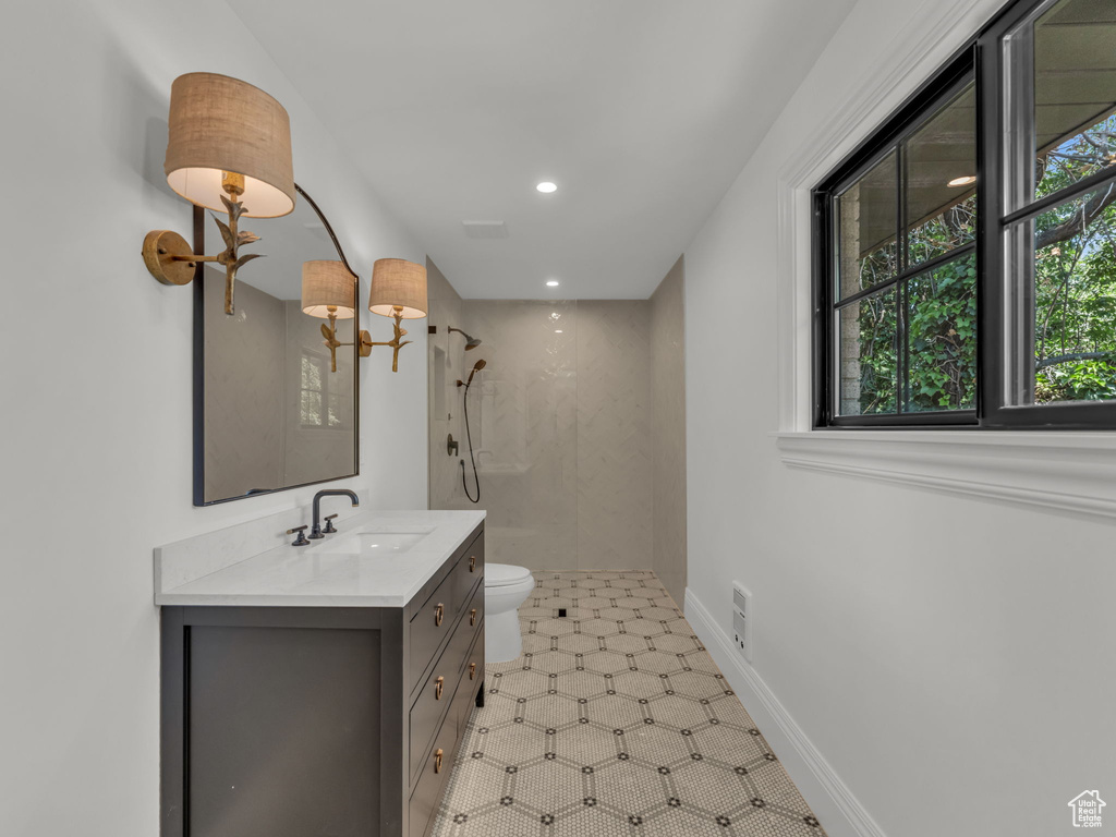 Bathroom with a tile shower, vanity, recessed lighting, and tile patterned floors
