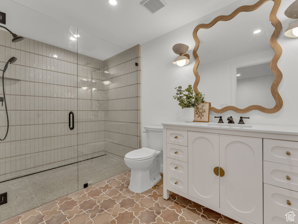 Bathroom with tiled shower, vanity, and recessed lighting