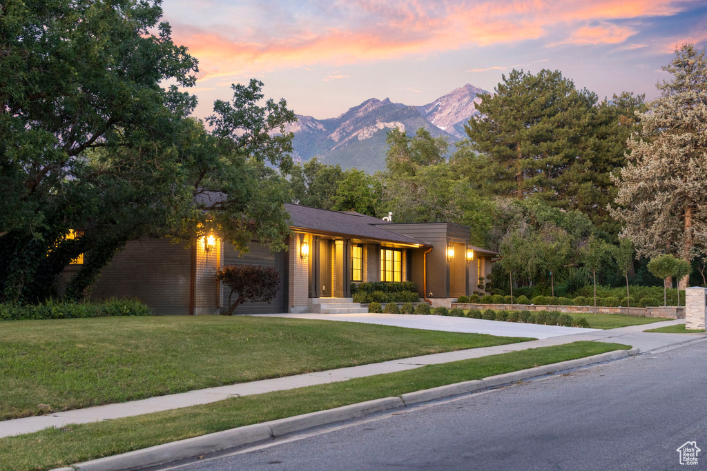 View of front facade featuring a lawn, a mountain view, and concrete driveway