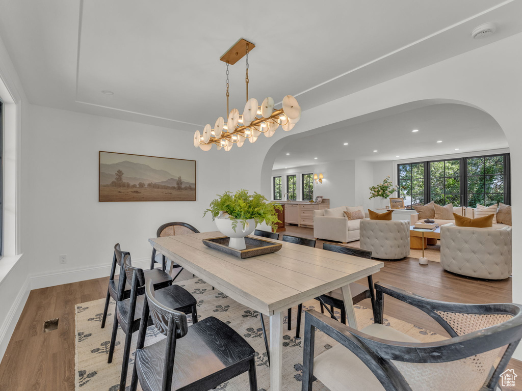 Dining space with arched walkways, recessed lighting, and wood finished floors