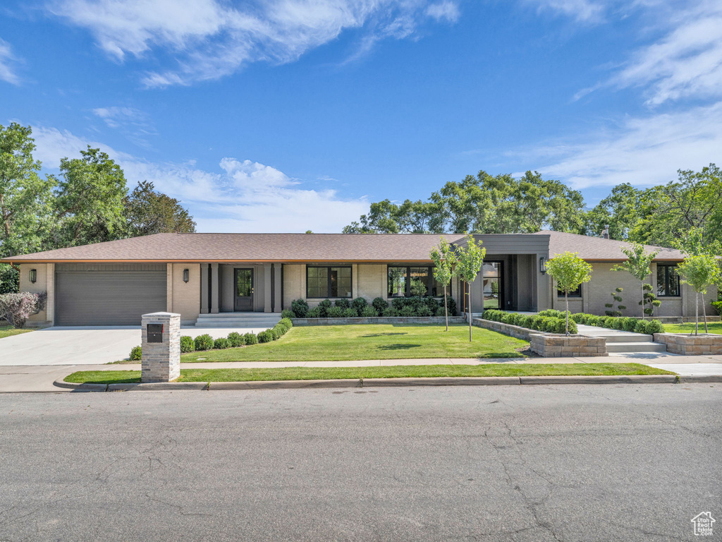 View of front of home with a garage, concrete driveway, a front yard, brick siding, and roof with shingles