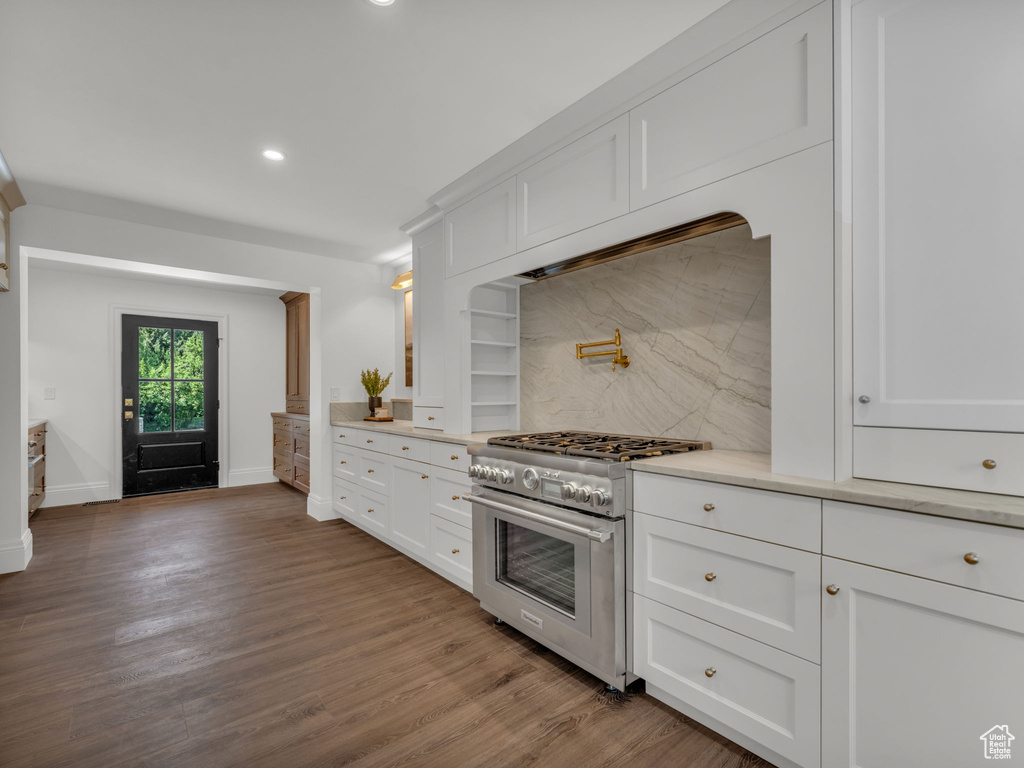 Kitchen with stainless steel range, backsplash, light countertops, recessed lighting, and white cabinetry