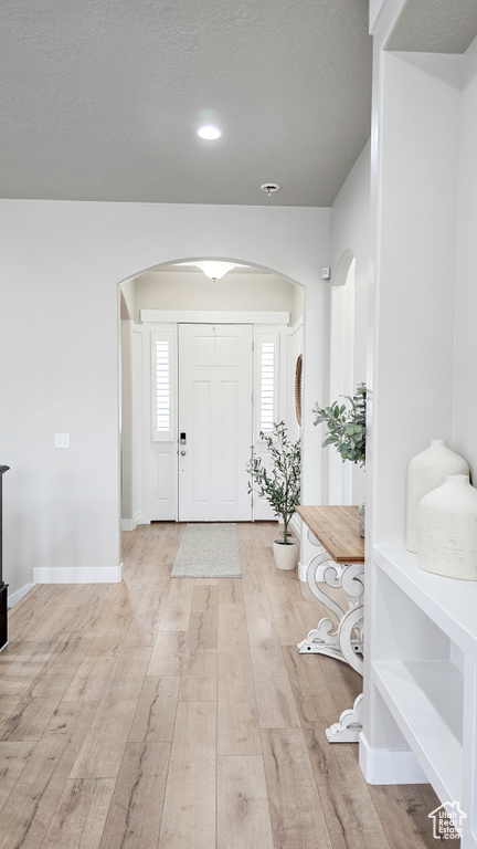 Entryway with arched walkways, wood finished floors, and recessed lighting