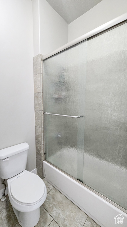 Bathroom featuring combined bath / shower with glass door and tile patterned floors