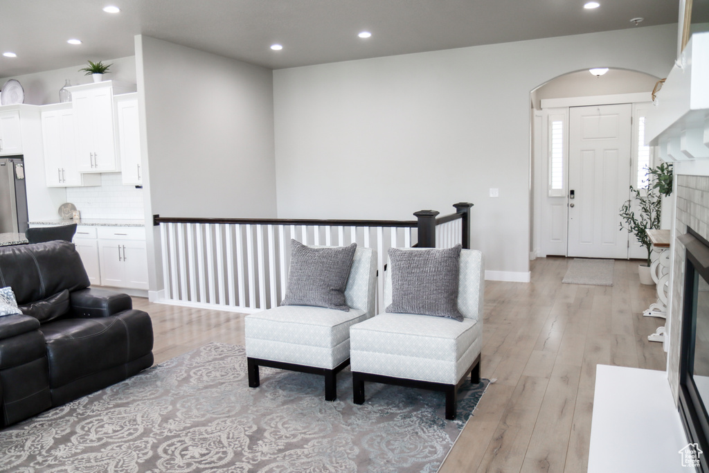 Living area featuring recessed lighting, light wood finished floors, arched walkways, and a glass covered fireplace