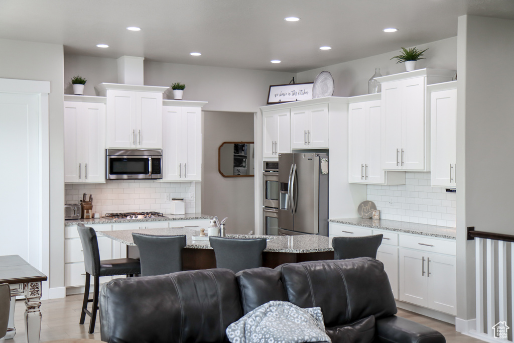 Kitchen with appliances with stainless steel finishes, backsplash, white cabinets, and recessed lighting