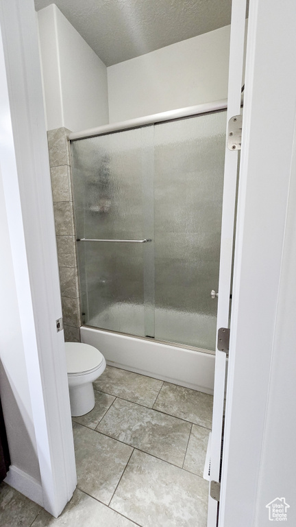 Full bathroom with toilet and shower / bath combination with glass door