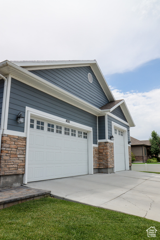 View of front of property with stone siding, an attached garage, and driveway