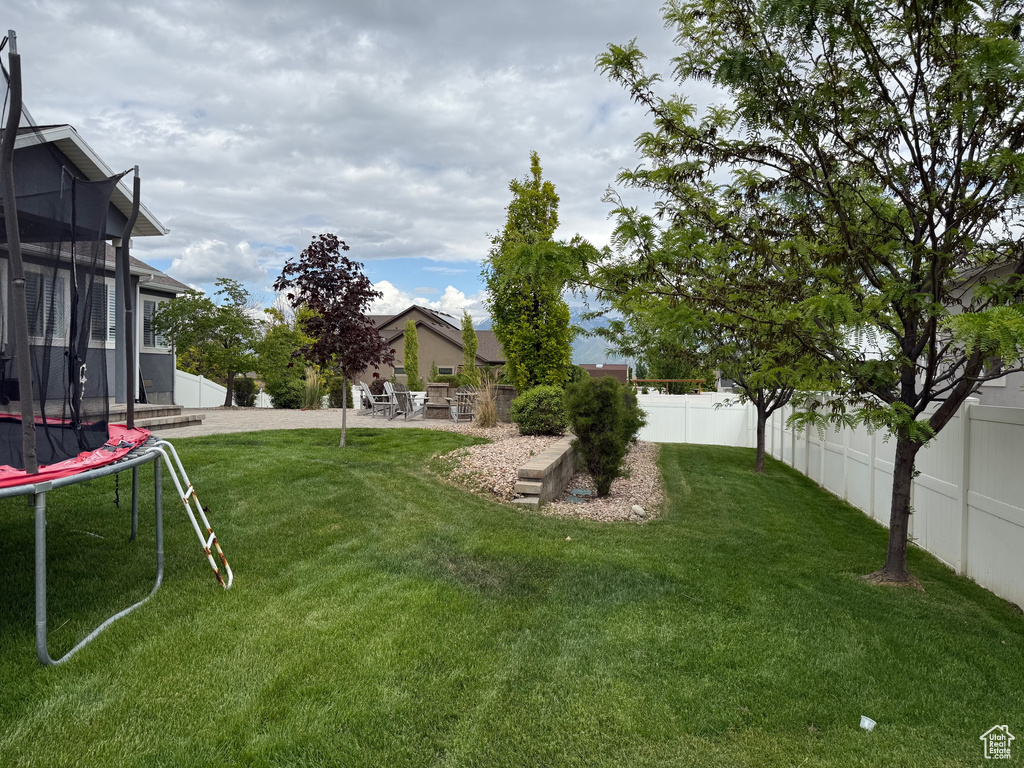 Fenced backyard with a trampoline and a patio area