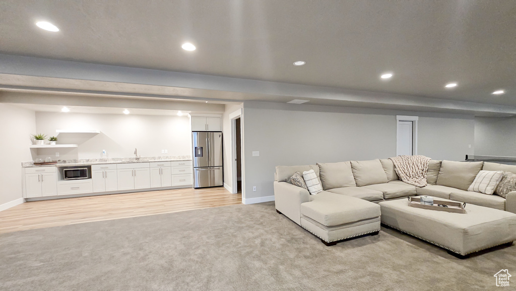 Living area featuring bar with sink, recessed lighting, light colored carpet, and light wood finished floors