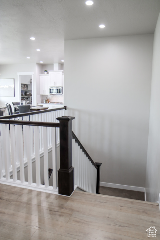 Stairs featuring wood finished floors and recessed lighting