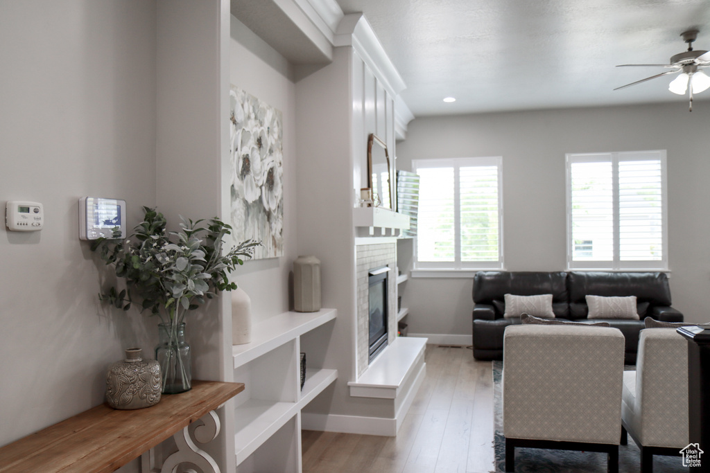 Living room featuring a ceiling fan, light wood-style floors, a glass covered fireplace, and recessed lighting