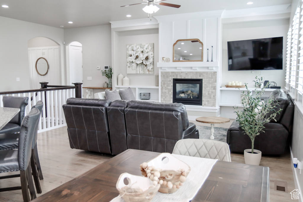 Living room featuring arched walkways, a ceiling fan, recessed lighting, light wood-style flooring, and a tile fireplace