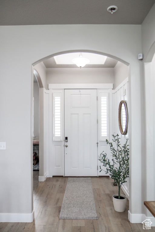 Entryway with arched walkways and light wood-style flooring