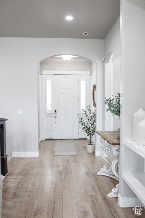 Foyer with arched walkways, wood finished floors, plenty of natural light, and recessed lighting