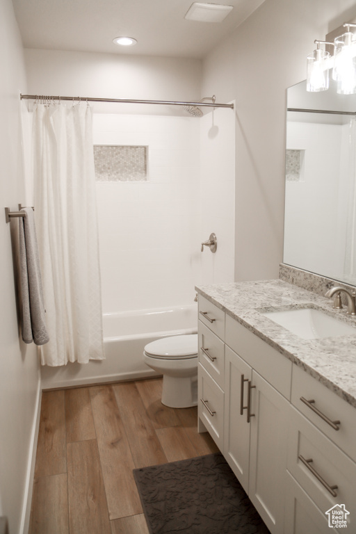 Full bathroom with vanity, wood finished floors, shower / bath combo with shower curtain, and recessed lighting