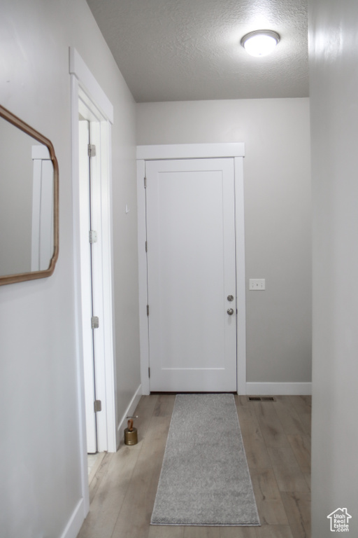 Corridor featuring a textured ceiling and light wood-type flooring