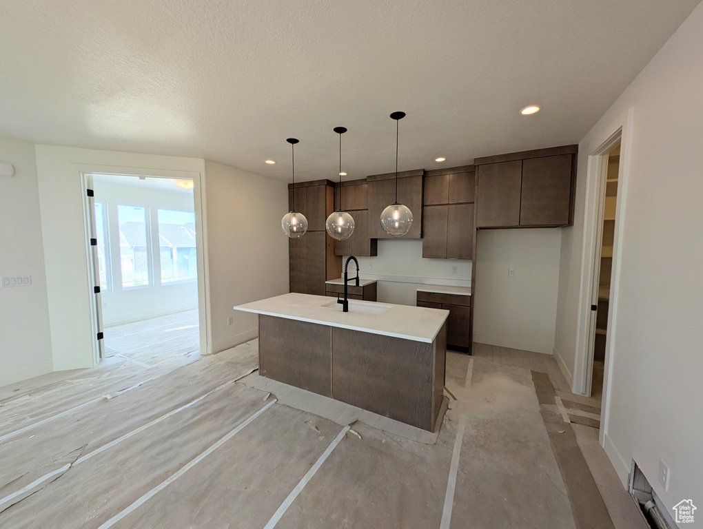 Kitchen featuring dark brown cabinetry, modern cabinets, a kitchen island with sink, light countertops, and recessed lighting