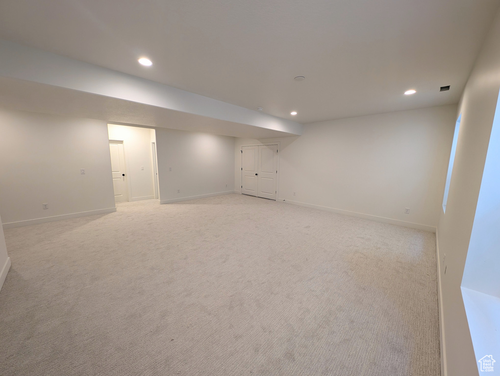 Finished below grade area with recessed lighting and light colored carpet