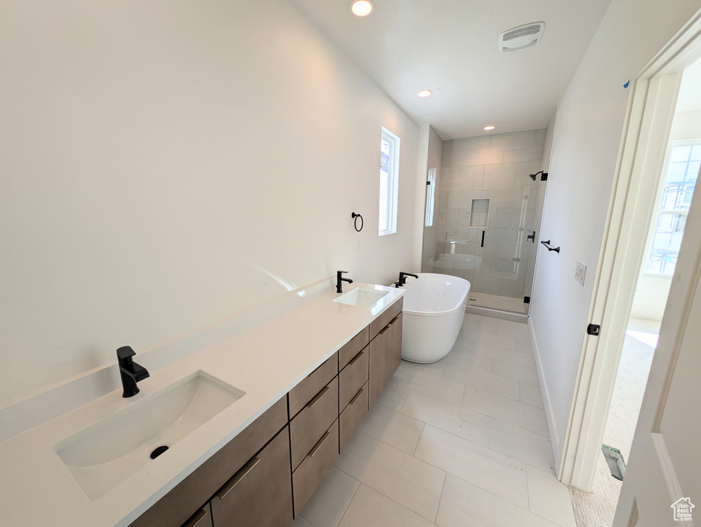 Bathroom with a shower stall, a soaking tub, healthy amount of natural light, double vanity, and recessed lighting