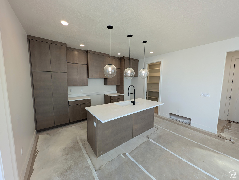 Kitchen with concrete flooring, an island with sink, modern cabinets, recessed lighting, and pendant lighting
