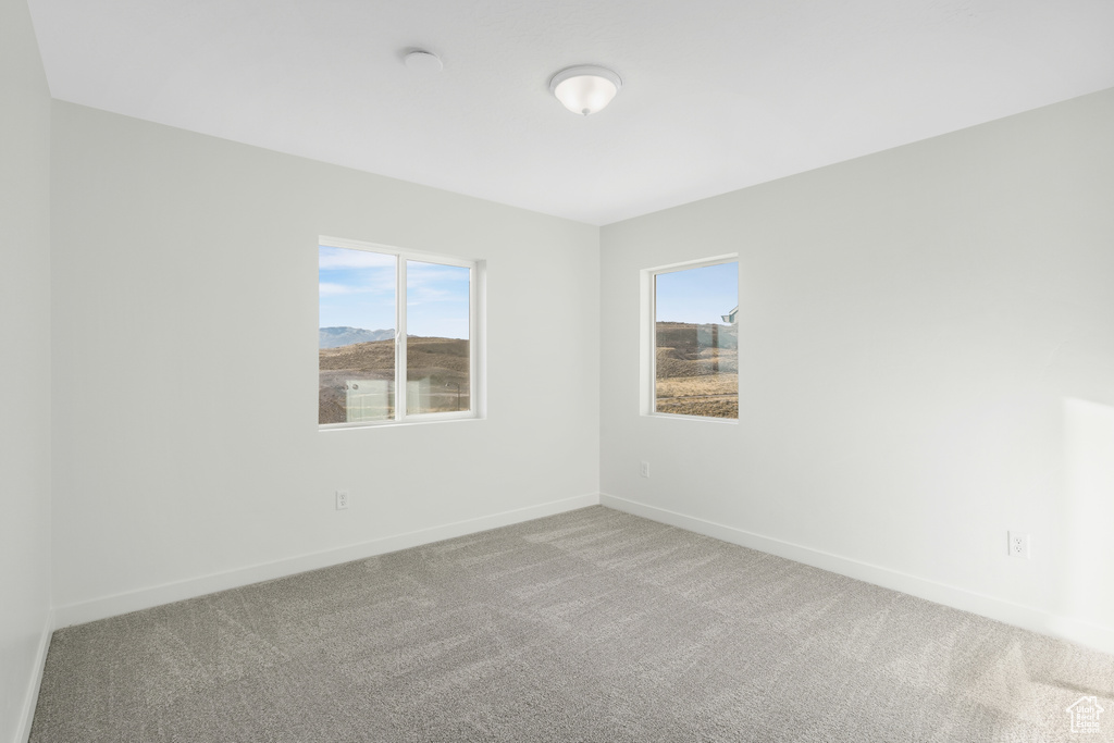 Empty room featuring healthy amount of natural light and carpet