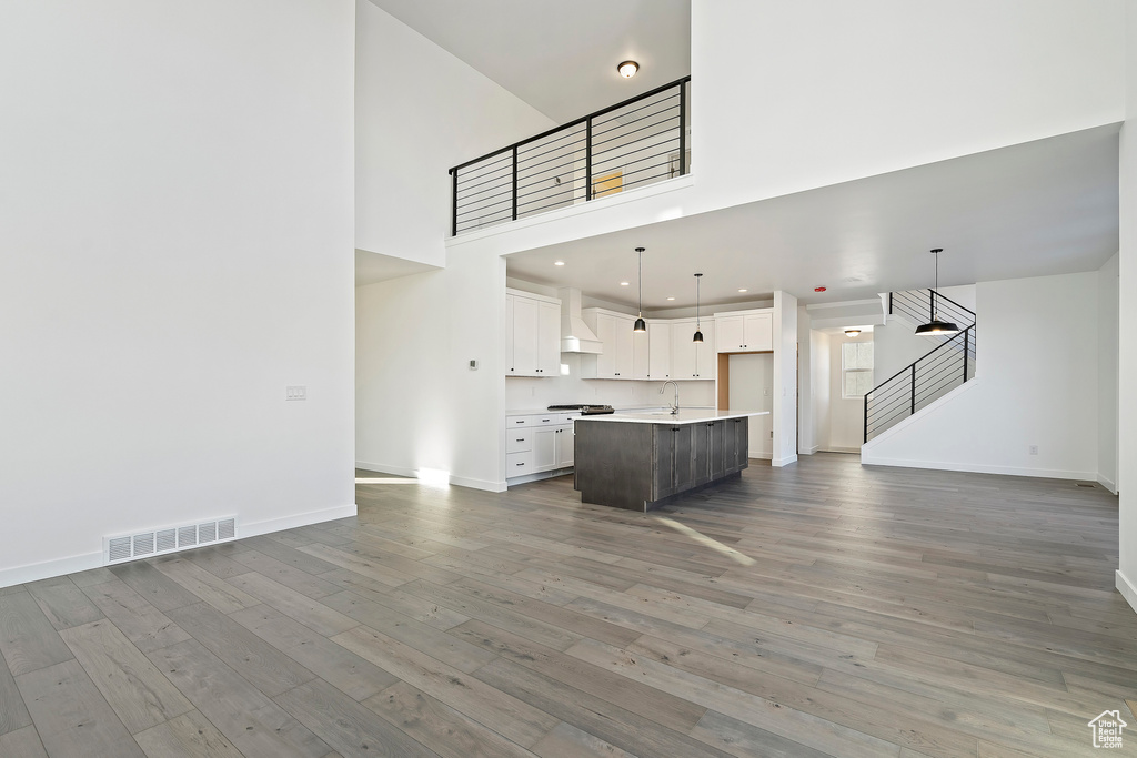 Unfurnished living room featuring light wood-style floors, stairway, and a towering ceiling